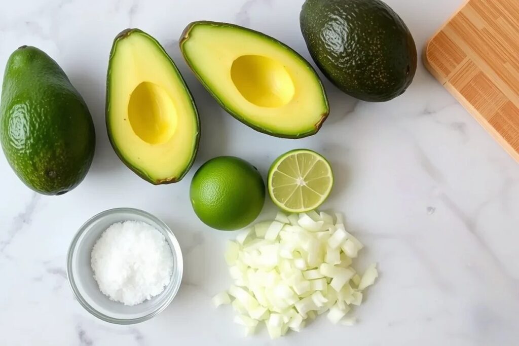 Ingredients for 4 ingredient guacamole: avocados, lime, salt, and onions arranged on a marble countertop